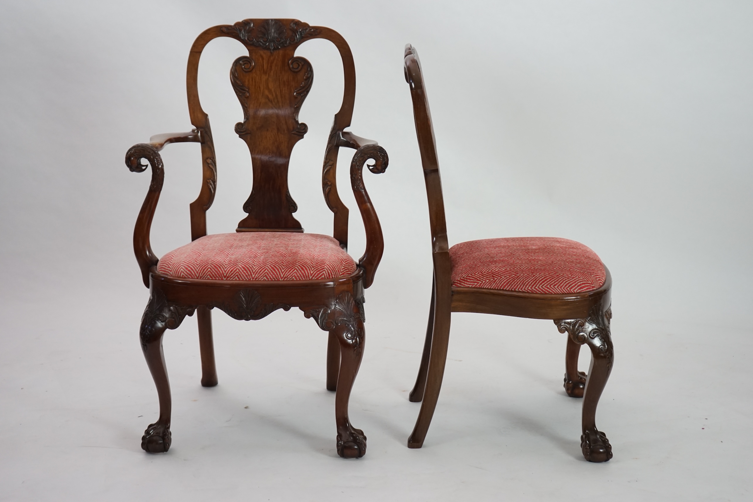 A set of twelve Queen Anne revival walnut dining chairs, including two carvers, with solid vase splats, eagle head shepherd’s crook arms, drop in seats and carved cabriole legs with claw and ball feet, carvers width 69cm